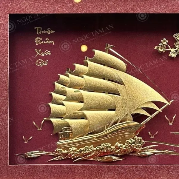 Tranh thuyền buồm thuận buồm xuôi gió dát vàng 24K (nền đỏ) 25x32cm Cận cảnh thuyền buồm, sóng nước và chữ "Thuận Buồm Xuôi Gió" dát vàng 24K